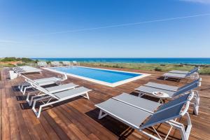 a deck with lounge chairs and a swimming pool at Palmares Beach House Hotel - Adults Only in Lagos