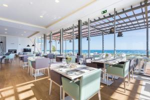 a restaurant with tables and chairs with a view of the ocean at Palmares Beach House Hotel - Adults Only in Lagos