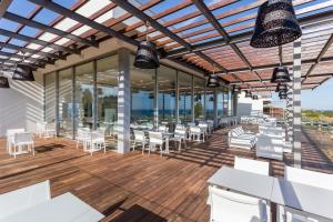 a patio with white tables and chairs on a wooden deck at Palmares Beach House Hotel - Adults Only in Lagos
