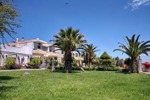 a house with palm trees in front of a yard at Kalloni Bay in Skala Kallonis