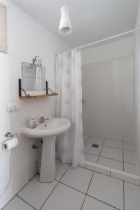 ein weißes Bad mit einem Waschbecken und einer Dusche in der Unterkunft Oasis Club Cottages in Udabno