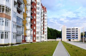 a row of tall apartment buildings with a grass field at NEW Apartment on Zhasmynova Street 5b in Lviv