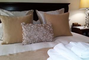 uma cama branca com almofadas e uma almofada cinzenta em Riversong Guest House em Cidade do Cabo