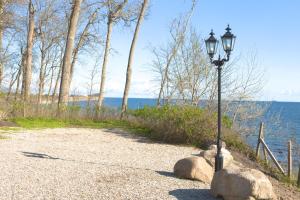 a street light on a gravel road next to the water at Waldpavillon in Fehmarn