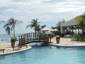 a pool at a resort with a bridge and palm trees at Apartamento Waiwai Cumbuco in Cumbuco