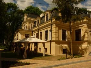 una gran casa blanca con un paraguas delante en Willa Filiks Restauracja & Pokoje en Nałęczów