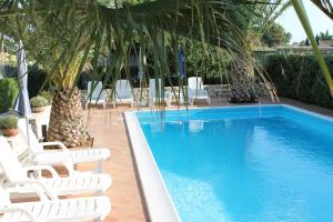 una piscina con sillas blancas junto a un complejo en Case Selinuntine Apartments, en Marinella di Selinunte