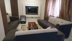 sala de estar con 2 sofás y TV en Al Fawanes Hotel Apartments, en Amán
