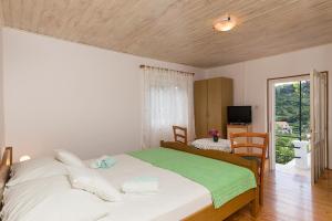 a bedroom with a large bed with a green blanket at Apartments Miskovic in Koločep