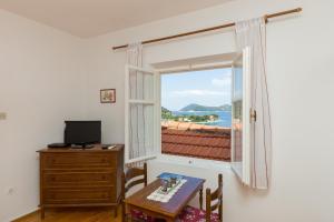 a room with a desk and a window with a table and a television at Apartments Miskovic in Koločep