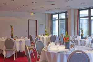 a room with tables and chairs with white tablecloths at Sunday Hotel Bad Soden in Bad Soden am Taunus