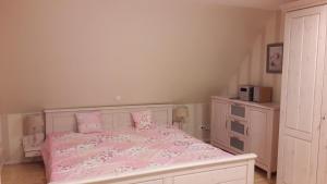 Un dormitorio con una cama rosa con sábanas y almohadas rosas. en Gästezimmer Grimmelmann, en Eystrup
