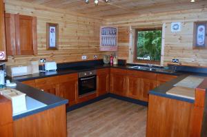 cocina grande con armarios de madera y fregadero en Fir Tree Lodge, en Blairgowrie