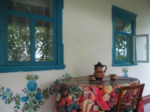 ein Esszimmer mit einem Tisch und 2 Fenstern in der Unterkunft Kалиновий Kущ in Dmitrenki