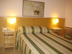 カルタヘナにあるPensión Balcones Azulesのベッド1台とナイトテーブル2台が備わるホテルルームです。