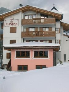 un edificio nella neve con un cortile coperto di neve di Hotel Villa Fosine a Pinzolo