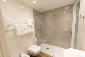 a white bathroom with a shower and a toilet at Grand Hotel Liberty in Riva del Garda