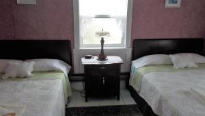 a bedroom with two beds and a window and a table at Margaree Harbour View Inn B&B in Margaree Harbour
