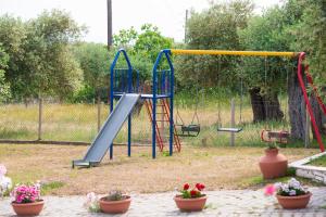 a playground with a slide in a park with flowers at Pension Maria in Astris