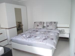 a white bedroom with a bed and a dresser at Apartament z balkonem przy Latarni 150m od morza in Kołobrzeg