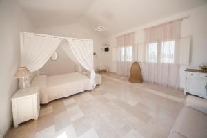 a white bedroom with a bed with a canopy at Antica Masseria Ficazzana - Tenuta in Marina di Pescoluse