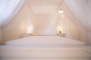 a bedroom with a white bed with white curtains at Antica Masseria Ficazzana - Tenuta in Marina di Pescoluse