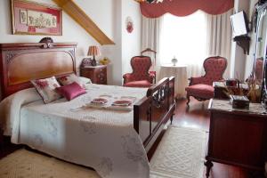 a bedroom with a large bed with red chairs at Casa De Cacheiro in Silleda