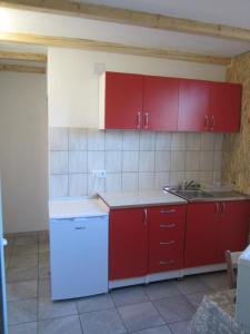 a kitchen with red cabinets and a white refrigerator at Bravo Guest House in Bihać