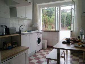 a kitchen with a washing machine and a window at As Mimosas in Sesimbra