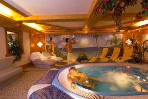 a man laying in a jacuzzi tub in a room at Hotel Bergland in Lermoos