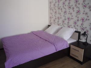 ヴォログダにあるАпартаменты на Преминина 14の小さなベッドルーム(紫色のベッド1台、ナイトスタンド付)