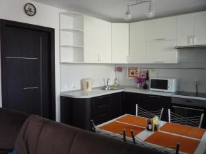 ヴォログダにあるАпартаменты на Преминина 14の白いキャビネットとテーブル付きのキッチンが備わります。