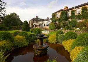 um jardim com uma fonte de pedra em frente a uma casa em George Hotel em Hexham