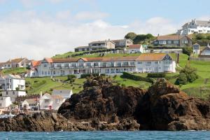 a large building on a hill next to the ocean at The Cottage Hotel in Hope-Cove