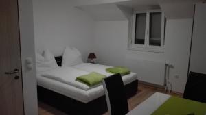 Schlafzimmer mit einem Bett mit weißer Bettwäsche und grünen Kissen in der Unterkunft Ferienwohnungen Feldsee in Illmitz