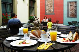 a wooden table with plates of food and orange juice at Old Riga Boutique Hotel "Vecriga" in Riga