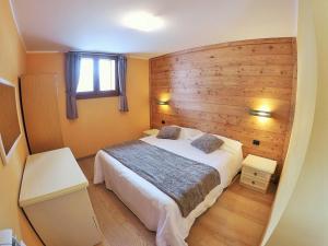 a bedroom with a bed and a wooden wall at Chalet Alpina Hotel & Apartments in La Thuile
