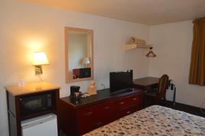 Habitación de hotel con cama y escritorio con TV. en American Elite Inn, en Hazard