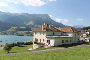 a house on a hill next to a body of water at Residence Garni Alpenstern in Resia