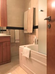 uma casa de banho com uma banheira, um lavatório e toalhas em São Martinho do Porto Beach Apartment em São Martinho do Porto