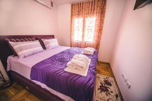 a bedroom with a bed with purple sheets and a window at Apartments Horizont in Budva