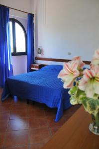 a bedroom with a bed with blue sheets and flowers at Appartamenti I Lauri in Porto Azzurro
