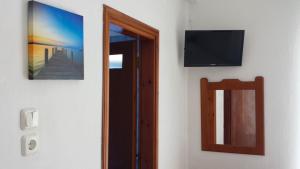 a room with a mirror and a television on a wall at Rooms Ntontas in Prinos