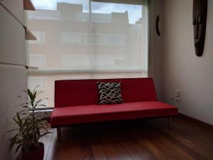 Sofá rojo en una habitación con ventana grande en Chic space by Unicentro, en Bogotá