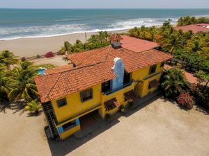 una casa amarilla con techo rojo en la playa en Solyar Luxury Spanish Beachfront Home, en Pochomil