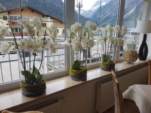 trois vases remplis de fleurs blanches sur un rebord de fenêtre dans l'établissement Hotel Steinbock, à Mittelberg