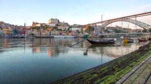 une rivière avec des bateaux et un pont dans une ville dans l'établissement Matosinho's Palace, à Matosinhos