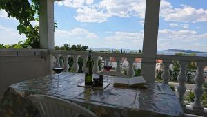 a table with wine glasses and a book on a balcony at Apartments Kocka in Primošten