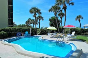 - une piscine avec une table, un parasol et des palmiers dans l'établissement Gulf and beach view apartment 403, à Longboat Key