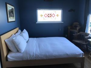 a bed in a blue bedroom with a window at The Inn at Tough City in Tofino